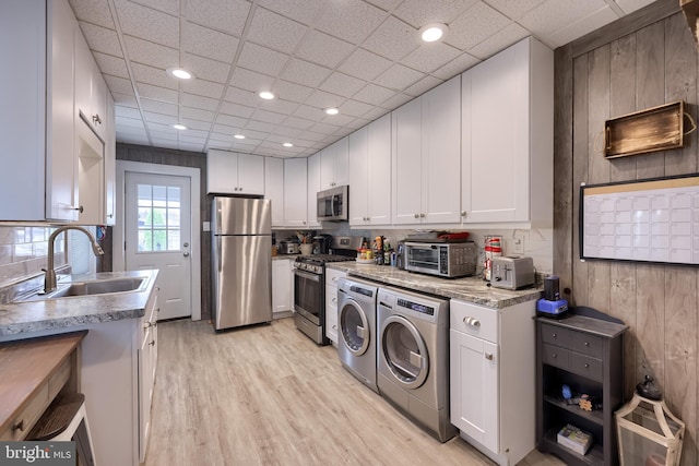 114 Walnut St, Columbia, PA 17512 - kitchen featuring appliances with stainless steel finishes, a sink, washer and dryer, light wood finished floors, and white cabinetry