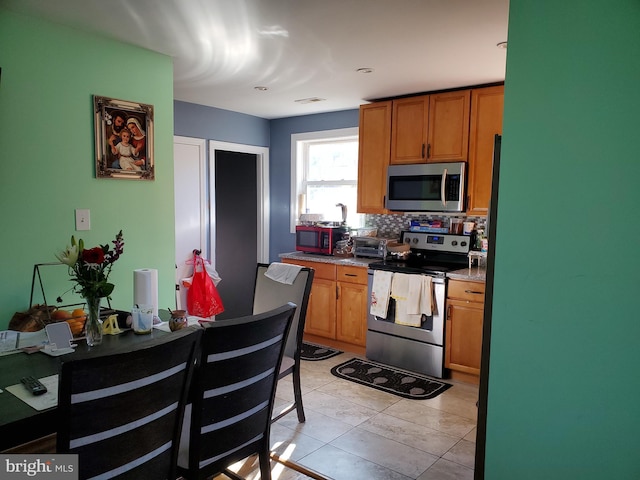 4905 66th Ave, Hyattsville, MD 20784 - kitchen with stainless steel appliances, backsplash, brown cabinets, and light tile patterned floors