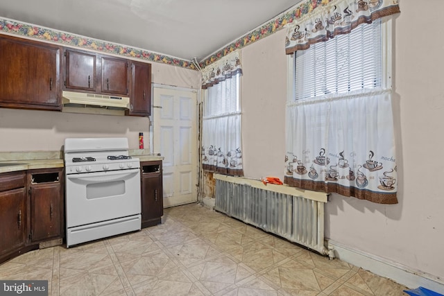 2531 N Lawrence St, Philadelphia, PA 19133 - kitchen featuring white gas range oven, under cabinet range hood, radiator, light countertops, and dark brown cabinets
