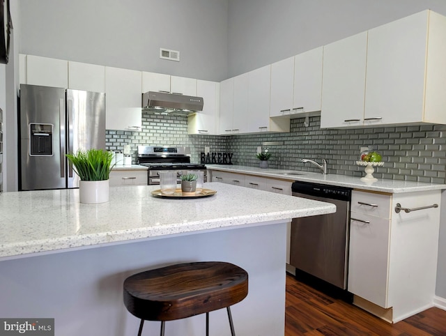 407 Talon Ct, Lawrence, NJ 08648 - kitchen with appliances with stainless steel finishes, under cabinet range hood, a breakfast bar, white cabinetry, and a towering ceiling
