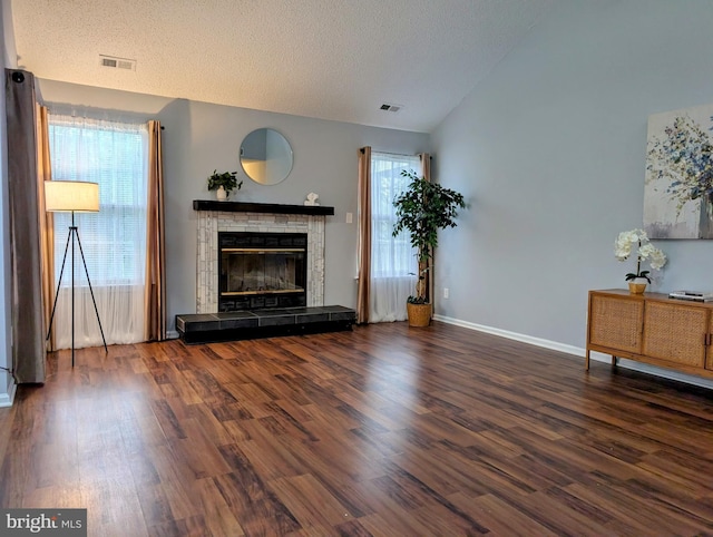 407 Talon Ct, Lawrence, NJ 08648 - unfurnished living room featuring lofted ceiling, wood finished floors, a tiled fireplace, a textured ceiling, and baseboards