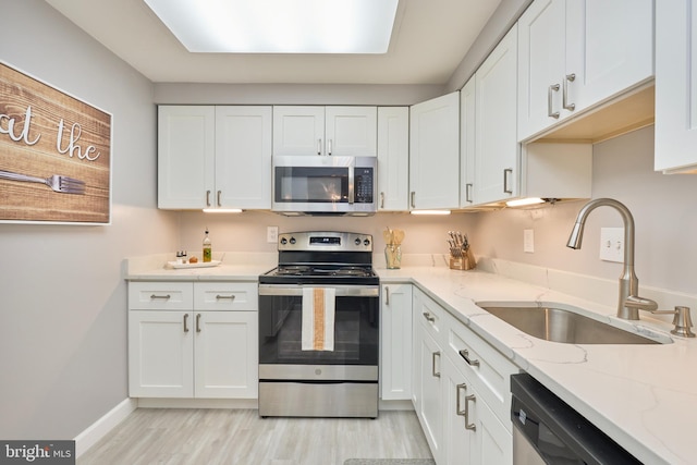 7621 Tremayne Pl Unit 205, Mclean, VA 22102 - kitchen with stainless steel appliances, a sink, white cabinets, light wood-type flooring, and light stone counters