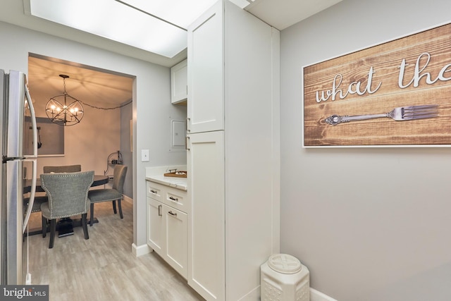 7621 Tremayne Pl Unit 205, Mclean, VA 22102 - kitchen with freestanding refrigerator, a chandelier, light wood-type flooring, white cabinets, and baseboards