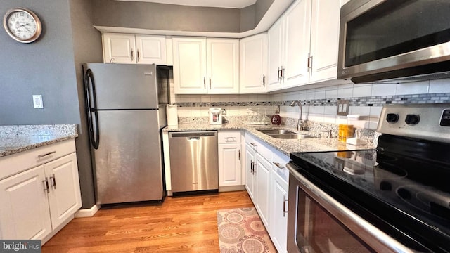 207 Walnut Hill Rd Unit B17, West Chester, PA 19382 - kitchen with appliances with stainless steel finishes, decorative backsplash, light wood-type flooring, white cabinetry, and light stone counters