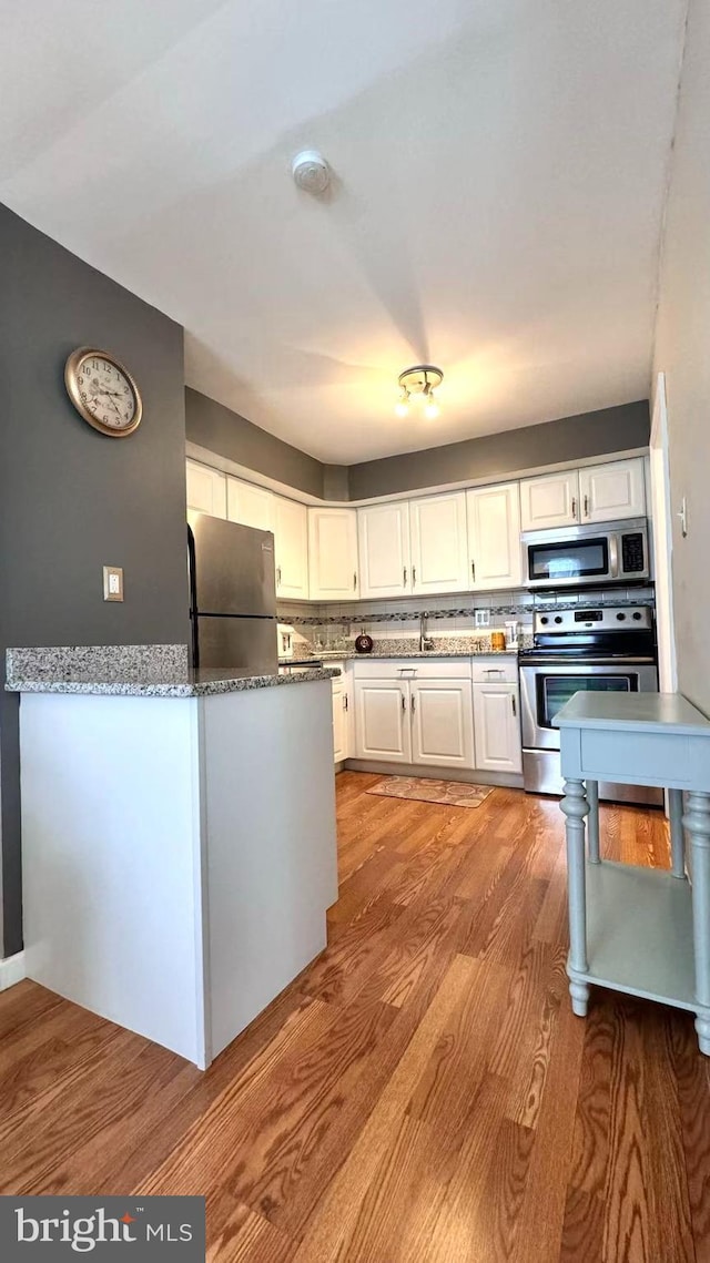 207 Walnut Hill Rd Unit B17, West Chester, PA 19382 - kitchen with appliances with stainless steel finishes, light wood-type flooring, white cabinets, and backsplash