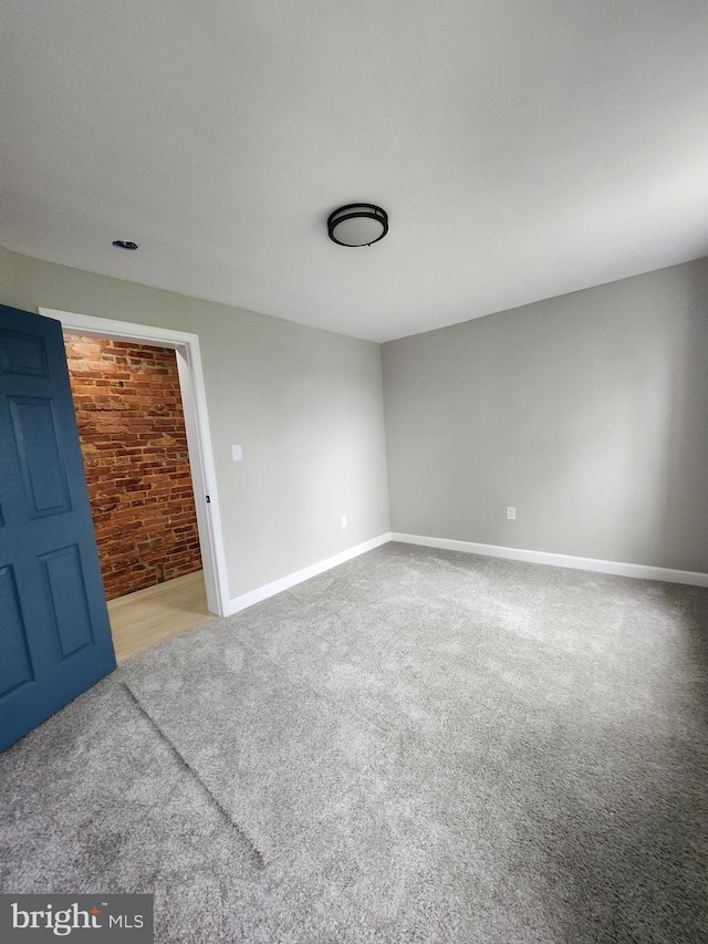 901 N Luzerne Ave, Baltimore, MD 21205 - carpeted empty room with baseboards and brick wall