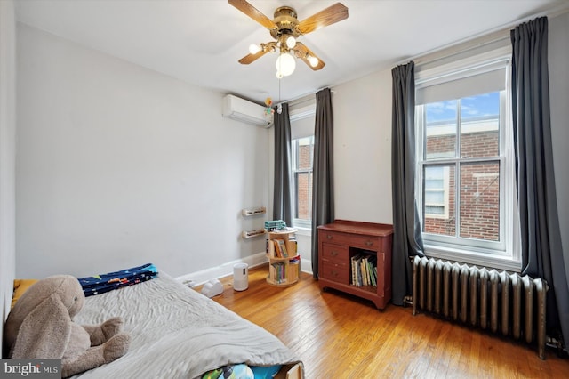 2347 E Norris St, Philadelphia, PA 19125 - bedroom with radiator, a wall mounted air conditioner, light wood-style flooring, and baseboards