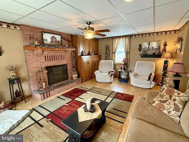 239 S Allison St, Greencastle, PA 17225 - living area featuring light wood-type flooring, a drop ceiling, a ceiling fan, and a brick fireplace