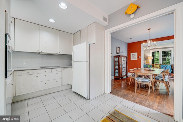 3100 Rodman St NW, Washington, DC 20008 - kitchen with freestanding refrigerator, black electric stovetop, a chandelier, tasteful backsplash, and white cabinets