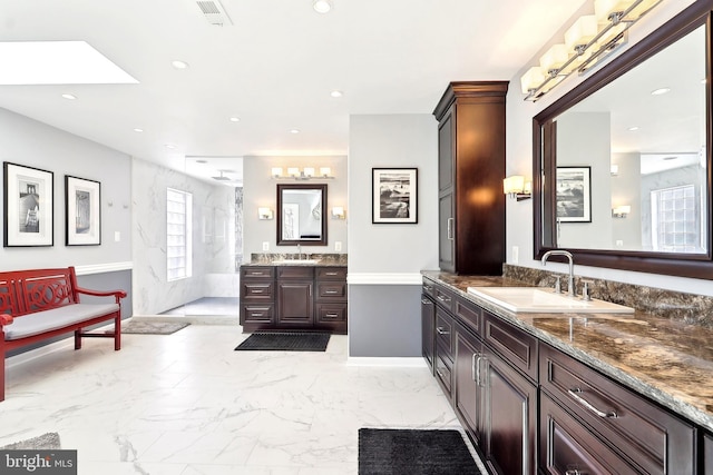 7951 Kelly Ann Ct, Fairfax Station, VA 22039 - full bath featuring marble look tiles, two vanities, recessed lighting, a skylight, and walk in shower