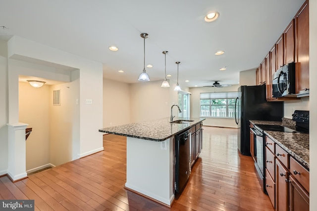 11606 Amaralles Dr, Reisterstown, MD 21136 - kitchen with black range with electric cooktop, a sink, stainless steel microwave, light wood-type flooring, and a center island with sink