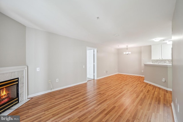 18707 Sparkling Water Dr Unit 3, Germantown, MD 20874 - unfurnished living room with light wood finished floors, a premium fireplace, a chandelier, and baseboards