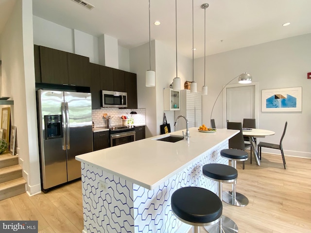 1111 Orren St NE Unit 300, Washington, DC 20002 - kitchen featuring appliances with stainless steel finishes, a sink, light wood-type flooring, dark cabinetry, and light countertops