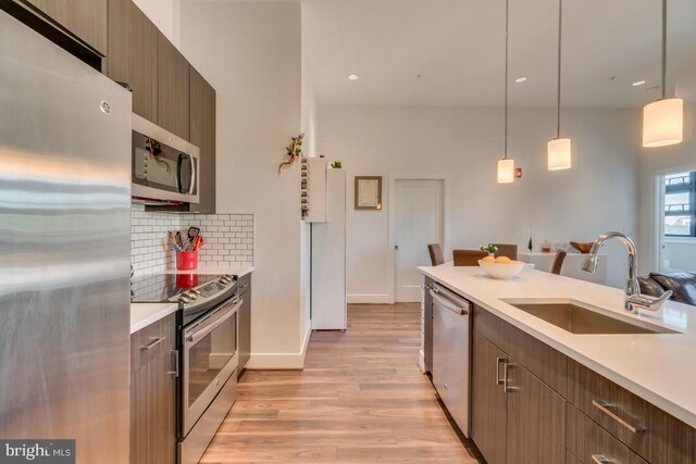 1111 Orren St NE Unit 300, Washington, DC 20002 - kitchen featuring appliances with stainless steel finishes, a sink, light wood-type flooring, light countertops, and decorative backsplash