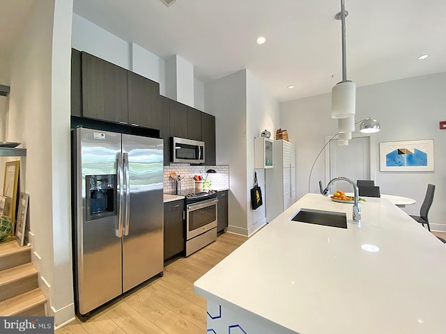 1111 Orren St NE Unit 300, Washington, DC 20002 - kitchen featuring appliances with stainless steel finishes, a sink, light wood-style flooring, light countertops, and dark cabinets