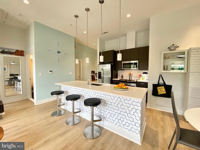 1111 Orren St NE Unit 300, Washington, DC 20002 - kitchen with appliances with stainless steel finishes, light countertops, light wood-style flooring, tasteful backsplash, and an island with sink