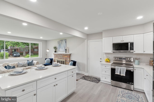 3015 Logan St, District Heights, MD 20747 - kitchen featuring appliances with stainless steel finishes, light wood finished floors, light countertops, tasteful backsplash, and white cabinets