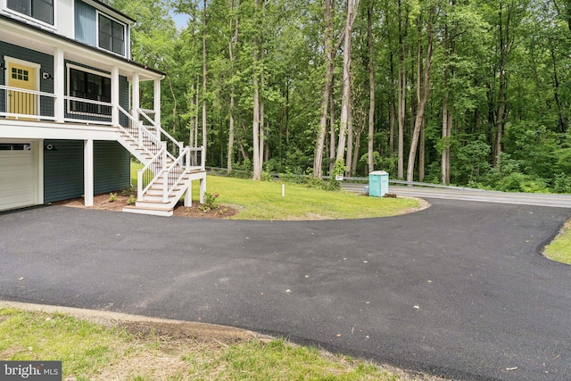 2655 5th St, Owings, MD 20736 - view of grassy yard with covered porch, stairs, an attached garage, and asphalt driveway