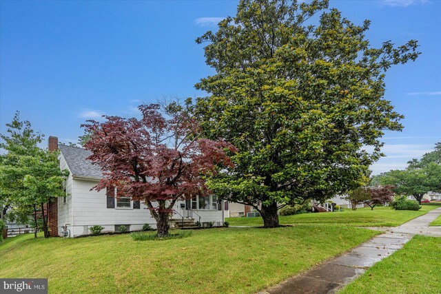 5507 Heatherwood Rd, Baltimore, MD 21227 - view of front of home with a front yard, roof with shingles, and a chimney