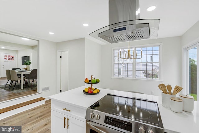 5507 Heatherwood Rd, Baltimore, MD 21227 - kitchen with stainless steel electric range oven, island exhaust hood, light wood-type flooring, a chandelier, and white cabinets