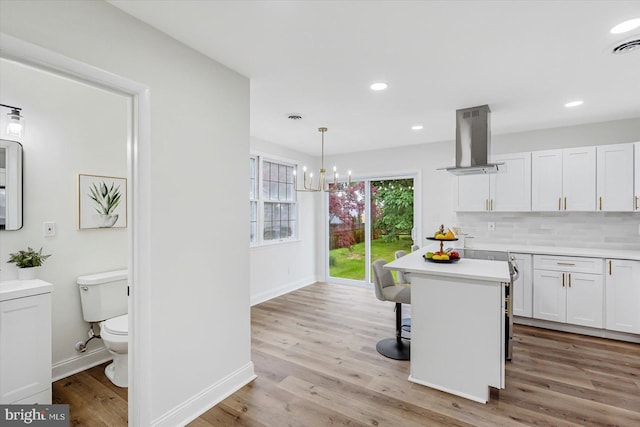 5507 Heatherwood Rd, Baltimore, MD 21227 - kitchen with island range hood, white cabinetry, light countertops, baseboards, and recessed lighting
