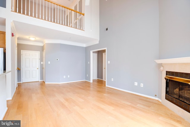 6549 Grange Ln Unit 401, Alexandria, VA 22315 - unfurnished living room featuring a fireplace, a towering ceiling, light wood-style flooring, crown molding, and baseboards