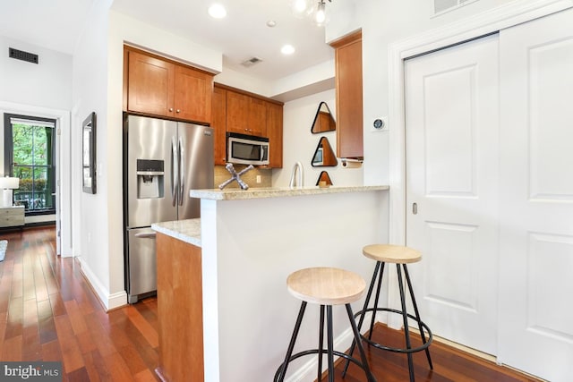 531 T St NW Unit 101, Washington, DC 20001 - kitchen with stainless steel appliances, brown cabinets, dark wood-type flooring, a kitchen breakfast bar, and recessed lighting