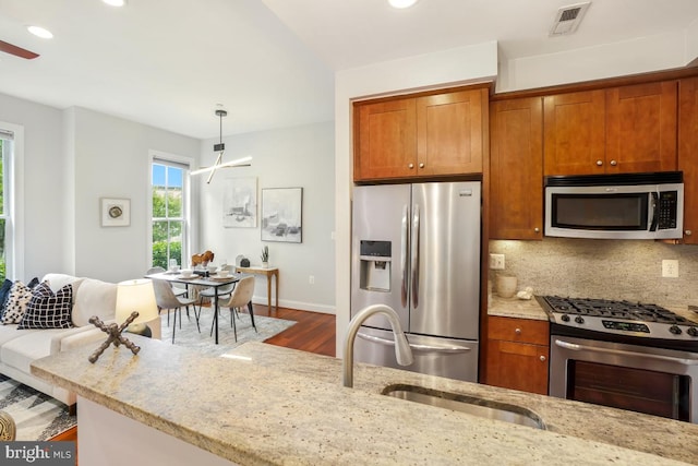531 T St NW Unit 101, Washington, DC 20001 - kitchen featuring appliances with stainless steel finishes, wood finished floors, light stone countertops, brown cabinetry, and recessed lighting