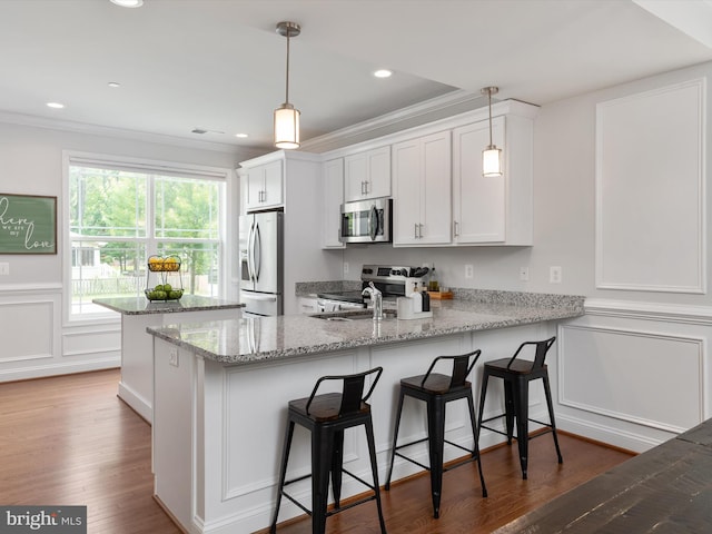 933 Winding Rd, Edgewater, MD 21037 - kitchen with appliances with stainless steel finishes, a peninsula, crown molding, a decorative wall, and white cabinets