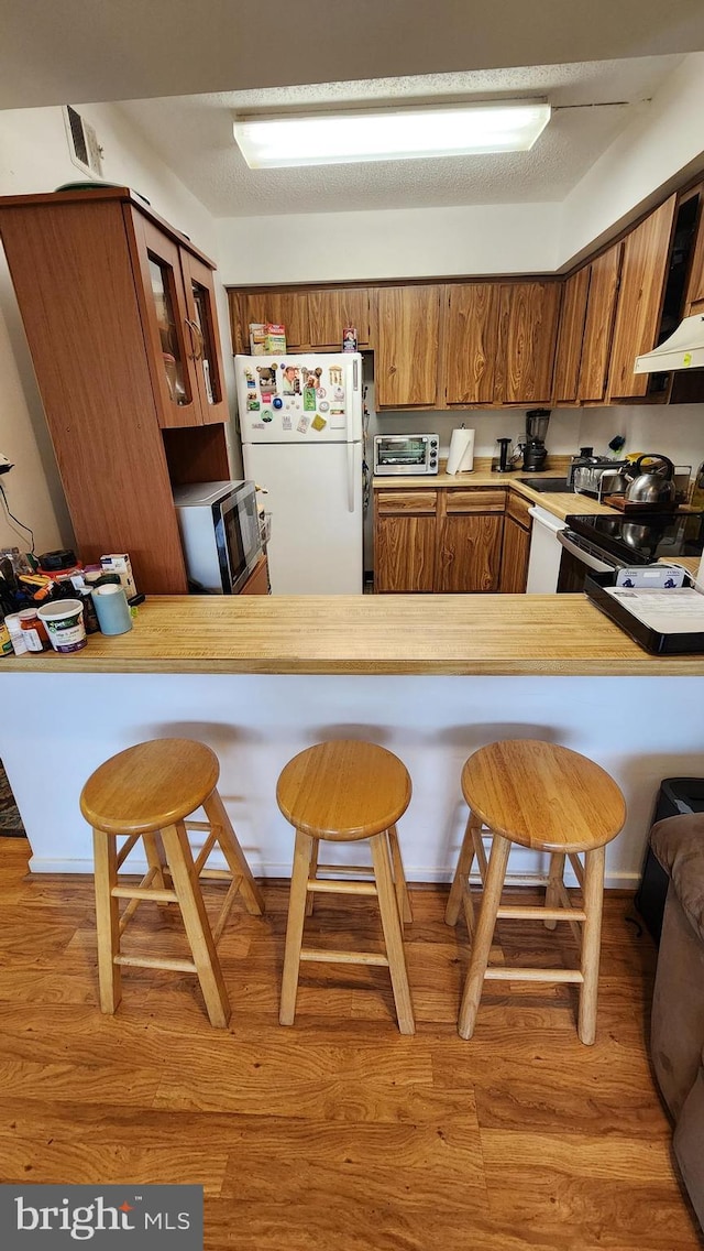 2921 N Leisure World Blvd Unit 418, Silver Spring, MD 20906 - kitchen with freestanding refrigerator, brown cabinetry, a peninsula, and light countertops