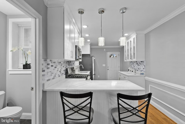 1330 Aisquith St, Baltimore, MD 21202 - kitchen with appliances with stainless steel finishes, a peninsula, glass insert cabinets, white cabinets, and tasteful backsplash