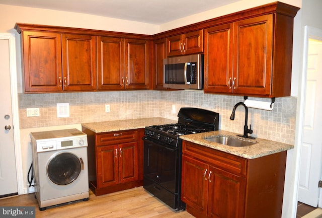 23 Foxglove St, Browns Mills, NJ 08015 - kitchen with stainless steel microwave, black gas range, washer / clothes dryer, a sink, and light stone counters