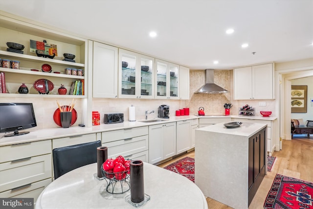 5610 Wisconsin Ave Unit 406, Chevy Chase, MD 20815 - kitchen with wall chimney range hood, light countertops, white cabinetry, decorative backsplash, and recessed lighting