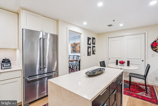 5610 Wisconsin Ave Unit 406, Chevy Chase, MD 20815 - kitchen featuring high quality fridge, light wood-type flooring, white cabinets, a kitchen island, and recessed lighting