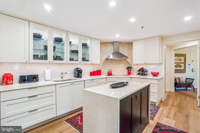 5610 Wisconsin Ave Unit 406, Chevy Chase, MD 20815 - kitchen featuring wall chimney exhaust hood, light countertops, white cabinetry, backsplash, and glass insert cabinets