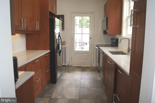 4305 Bradley Ln, Chevy Chase, MD 20815 - kitchen featuring appliances with stainless steel finishes, a sink, radiator, light countertops, and brown cabinetry