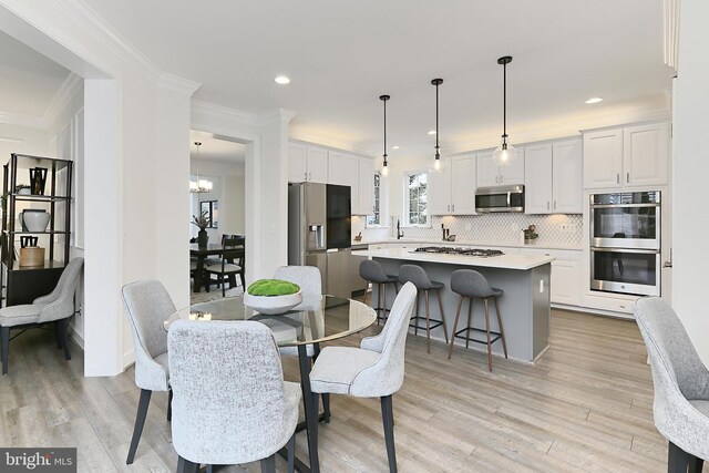 23219 Christopher Thomas Ln, Brambleton, VA 20148 - dining space with light wood-type flooring, a chandelier, ornamental molding, and recessed lighting