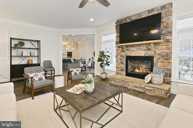 23219 Christopher Thomas Ln, Brambleton, VA 20148 - living area with wood finished floors, a ceiling fan, ornamental molding, and a stone fireplace