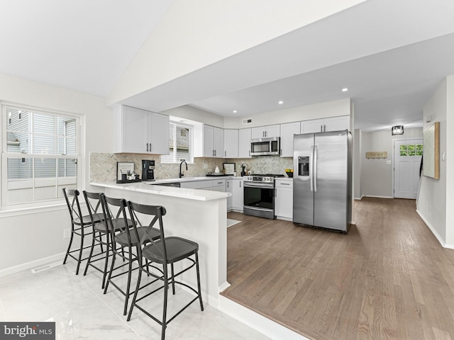 44 Wilson Dr, Sicklerville, NJ 08081 - kitchen featuring appliances with stainless steel finishes, a peninsula, backsplash, a breakfast bar, and healthy amount of natural light