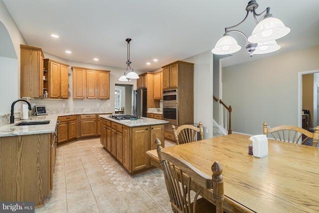 6422 Hard Bargain Cir, Indian Head, MD 20640 - kitchen featuring appliances with stainless steel finishes, a sink, light stone countertops, brown cabinets, and pendant lighting