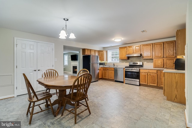 6422 Hard Bargain Cir, Indian Head, MD 20640 - kitchen featuring appliances with stainless steel finishes, under cabinet range hood, a sink, a chandelier, and light countertops