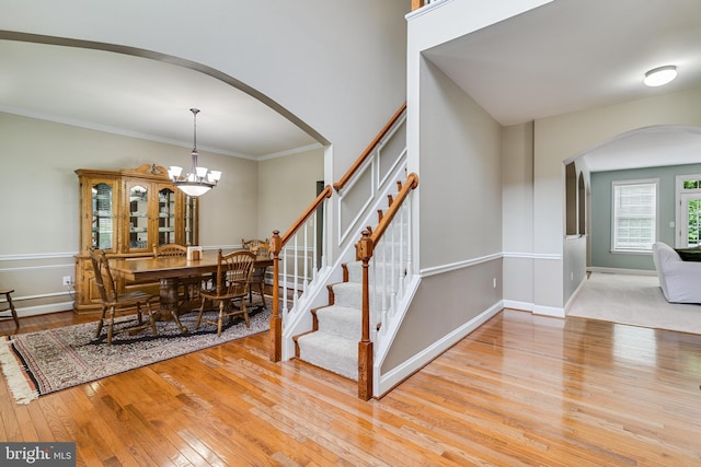6422 Hard Bargain Cir, Indian Head, MD 20640 - staircase featuring arched walkways, hardwood / wood-style flooring, a chandelier, crown molding, and baseboards