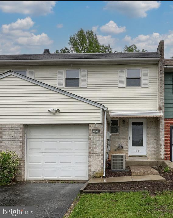 1134 Fox Run, Reading, PA 19606 - townhome / multi-family property featuring asphalt driveway, brick siding, a garage, and central air condition unit