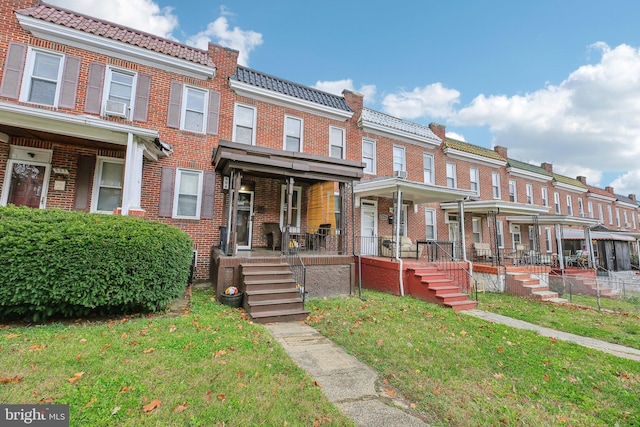 904 N Rosedale St, Baltimore, MD 21216 - view of property with a tiled roof, covered porch, a front yard, and brick siding