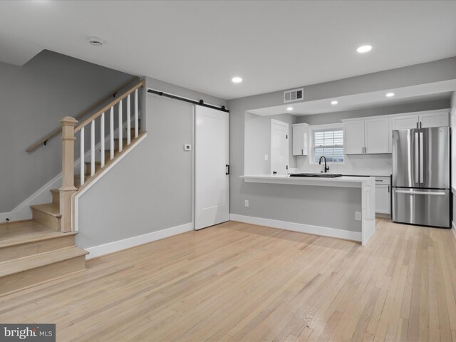 5105 11th St S, Arlington, VA 22204 - kitchen with freestanding refrigerator, a barn door, a sink, white cabinets, and light wood-type flooring
