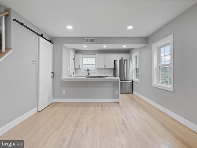 5105 11th St S, Arlington, VA 22204 - kitchen featuring freestanding refrigerator, a barn door, light countertops, light wood-type flooring, and white cabinets