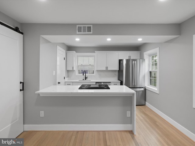 5105 11th St S, Arlington, VA 22204 - kitchen featuring freestanding refrigerator, a sink, light countertops, white cabinets, and a barn door