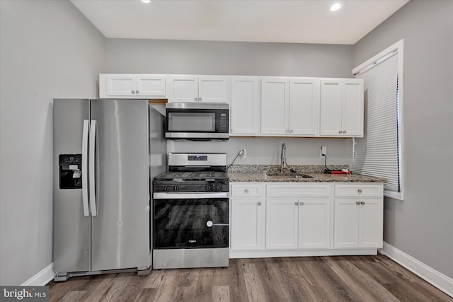 405 N Loudon Ave, Baltimore, MD 21229 - kitchen with stainless steel appliances, a sink, white cabinetry, light stone countertops, and wood finished floors