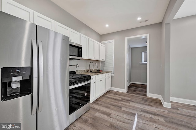 405 N Loudon Ave, Baltimore, MD 21229 - kitchen featuring appliances with stainless steel finishes, a sink, baseboards, white cabinets, and light wood finished floors