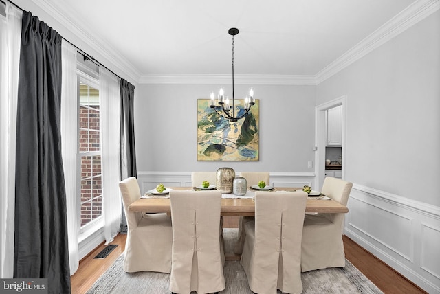 41311 Silverside Dr, Leesburg, VA 20175 - dining area featuring a chandelier, crown molding, light wood-style floors, and wainscoting